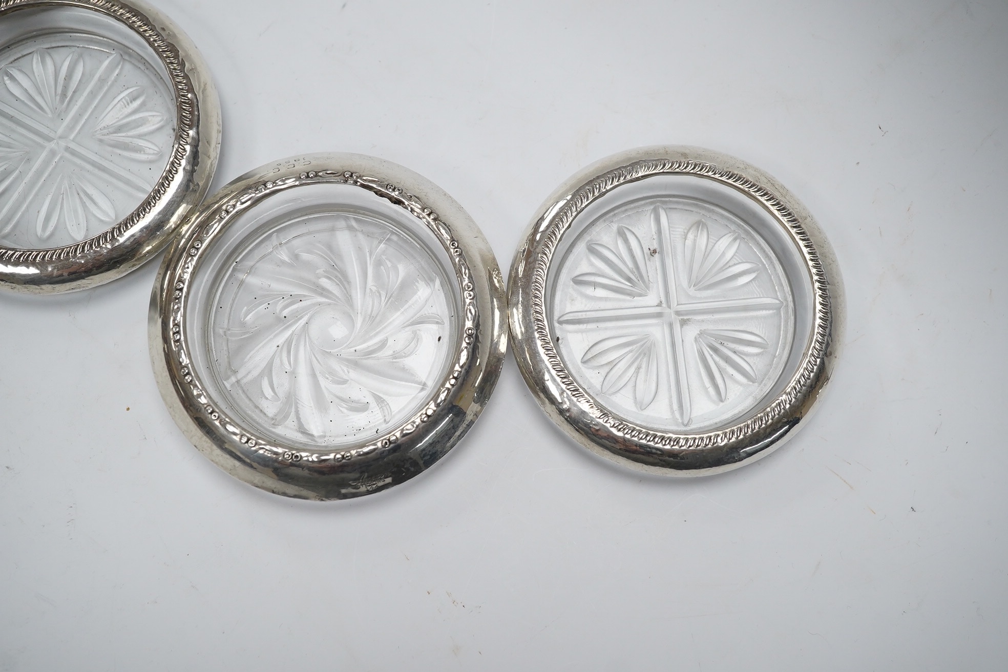 A set of four silver rimmed cut glass coasters, diameter 93mm. Condition - poor